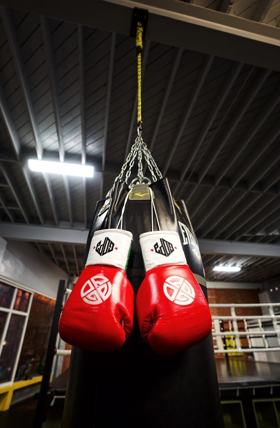 Red Gopa Boxing Club gloves hanging on the heavy bag