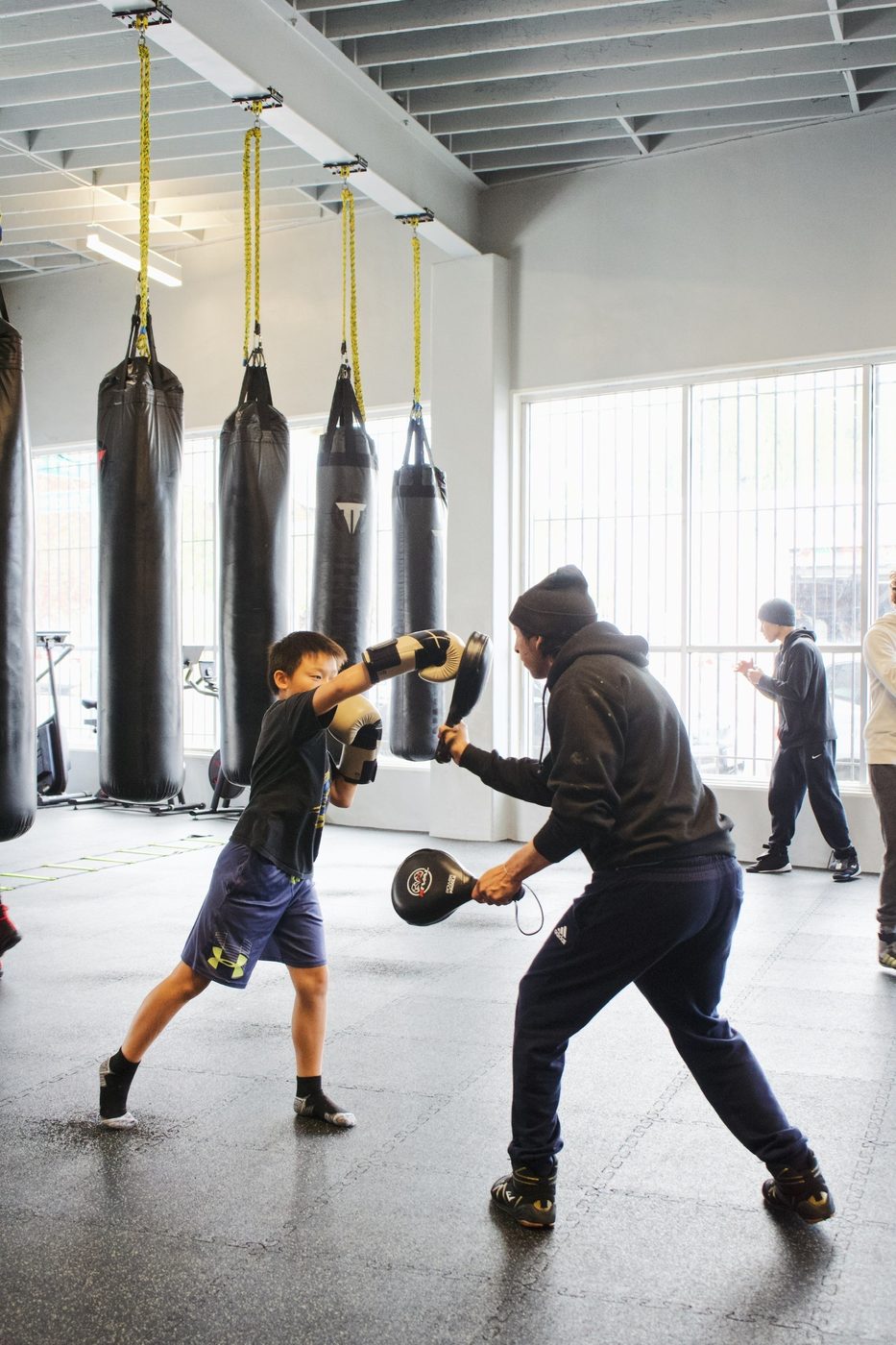 Coach working mitts with a young boxer at Gopa Boxing Club Oakland