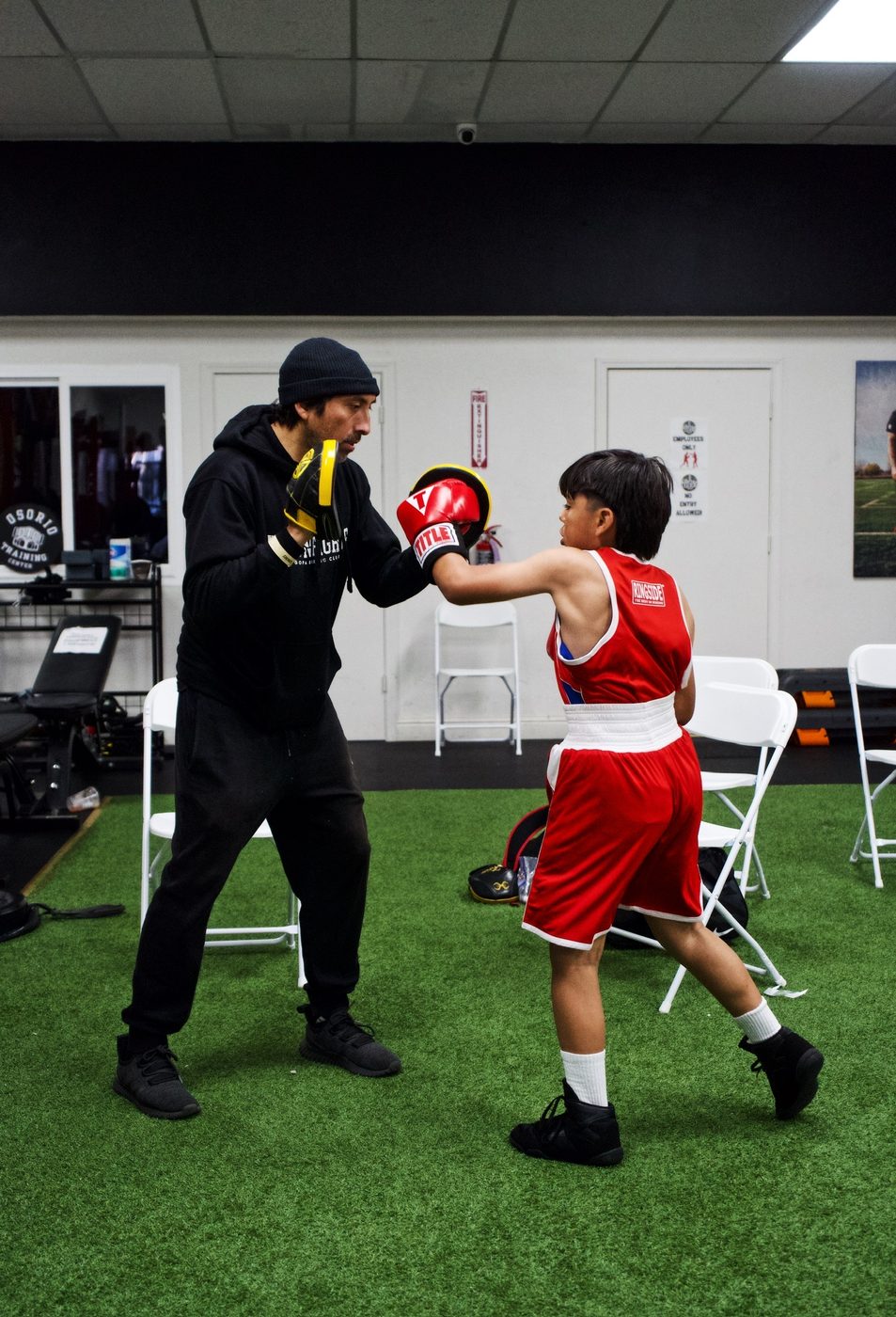 Coach holding mitts for a young boxer before a bout