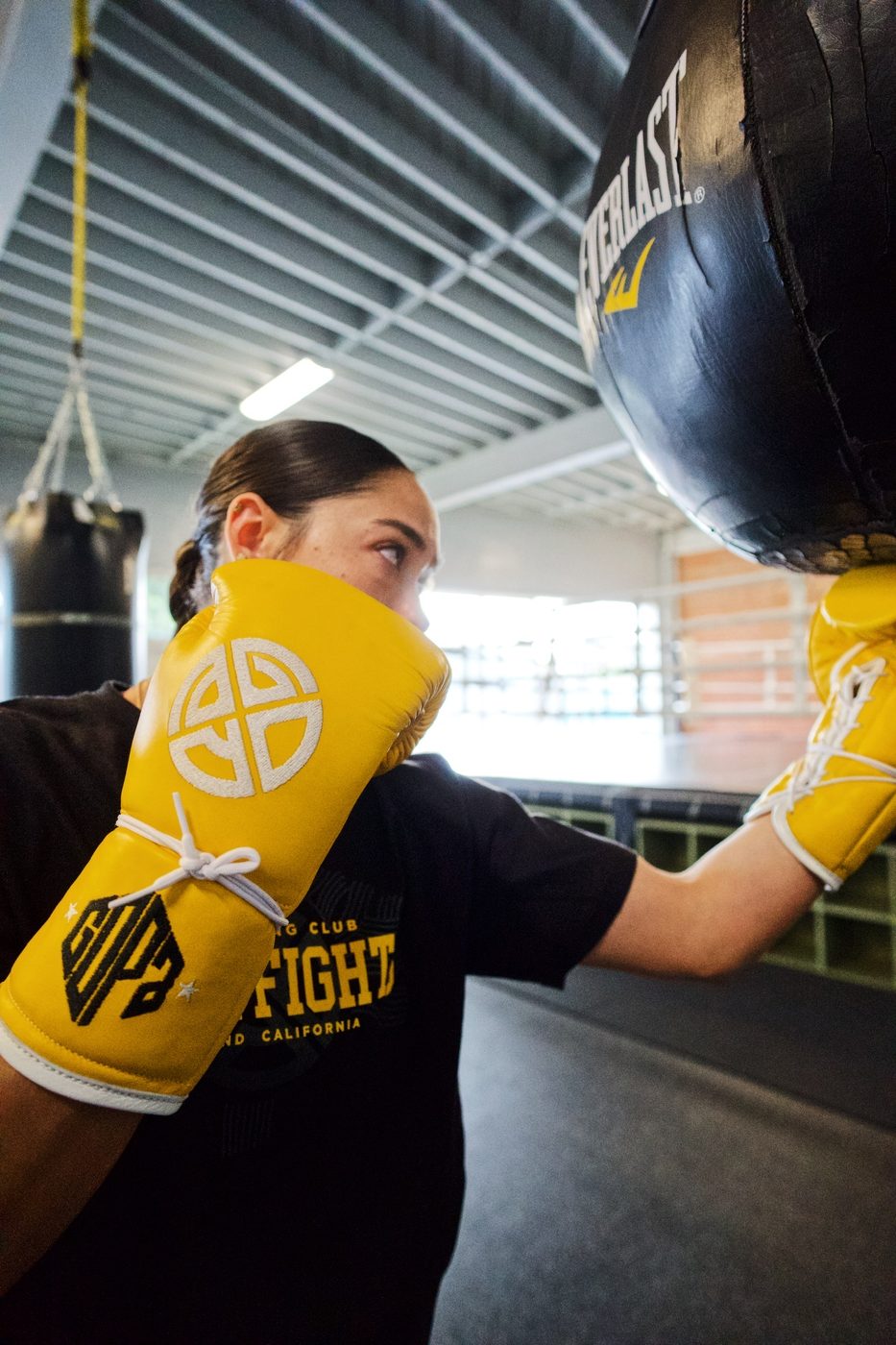 Young boxer working the heavy bag in gold Gopa gloves