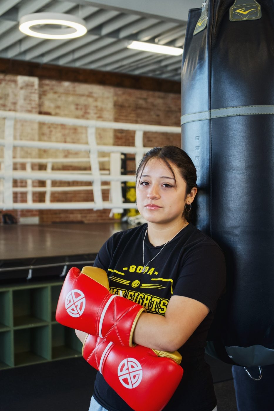 Young boxer with red Gopa gloves beside the heavy bag